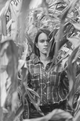 Obraz na płótnie Canvas Black and white shot of Woman in the dried corn stalks in a corn maze.