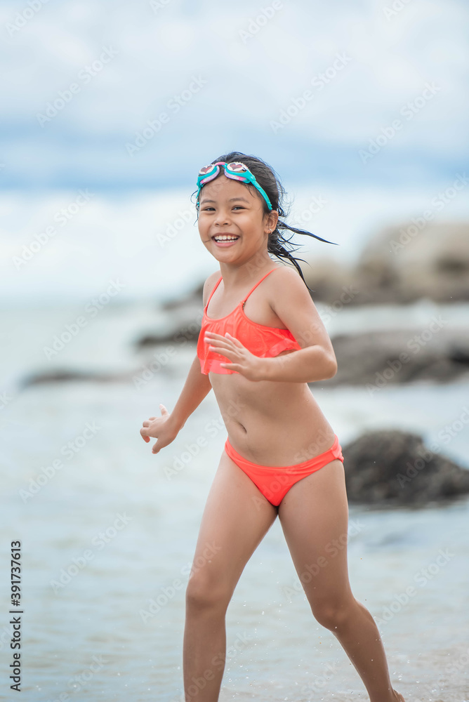 Wall mural child relaxing on the beach against sea and sky background. summer vacation and travel concept. happy little girl running on the beach.