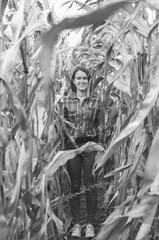 Black and white shot of Woman in the dried corn stalks in a corn maze.