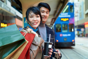 happy young asian couple waiting for bus in modern city
