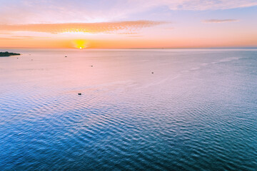 Small boats on calm ocean waters at sunset - aerial view