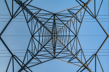 Bottom view of a Transmission tower with a blue sky. Square diagonals from the steel construction and the straight lines from the electrical cables.