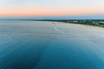Fototapeta na wymiar Aerial view of boat sailing across Port Phillip Bay near the coast at dusk in Australia