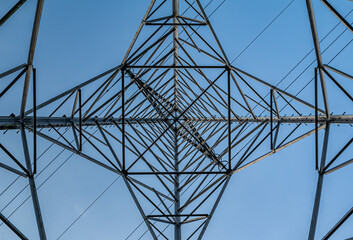 Bottom view of a Transmission tower with a blue sky. Square diagonals from the steel construction and the straight lines from the electrical cables.