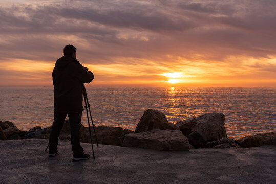 Adult man taking pictures at sunrise, sunset on the seashore