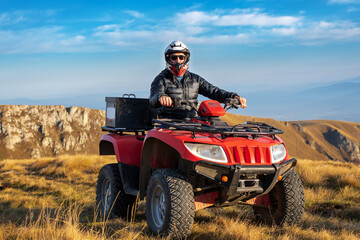 A man on a quad bike in the mountains. 