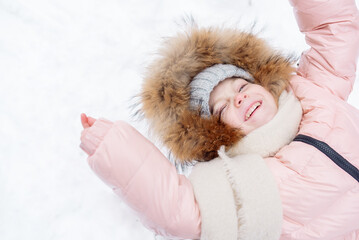 Fototapeta premium Little girl in a fur-trimmed hat laughs while sledding in winter 