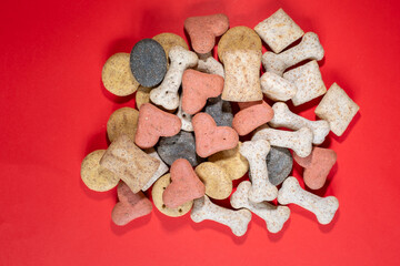 A pile of multi-coloured dog biscuits on a red background