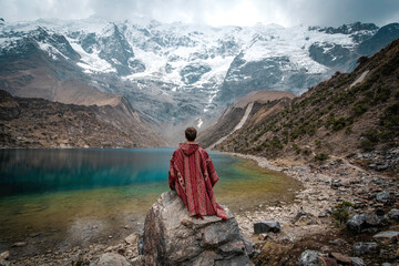 A young man with a poncho on vacation in Laguna Humantay, Peru