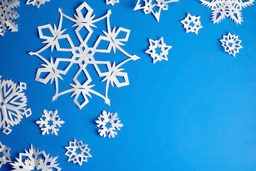 Fototapeta premium Composition with white paper snowflakes on blue background