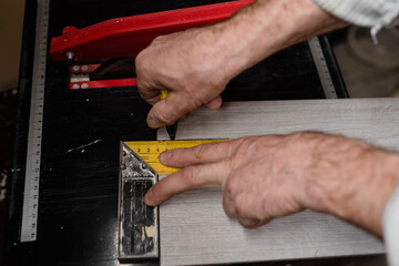 Fototapeta na wymiar Man hands marking tile to be cut. Laying ceramic floor tiles. Laying ceramic floor tiles - man hands closeup