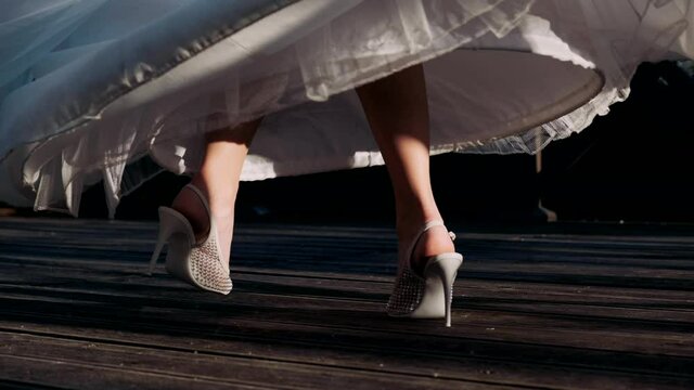 Women's legs in heels whirl in a wedding dress