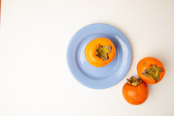 Persimmon fruit on white background and blue plate