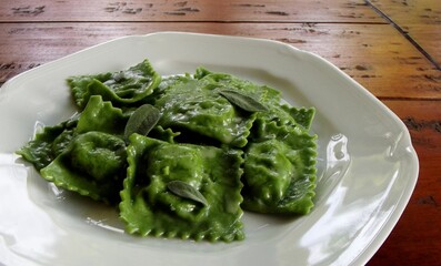 fresh homemade pasta. Italian dish with green ravioli on wooden table
