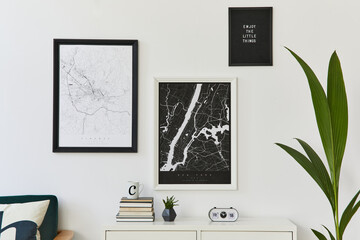 Retro modern compositon of living room interior with design armchair, two mock up poster map, clock, plant, decoration, white wall and personal accessories. Template.