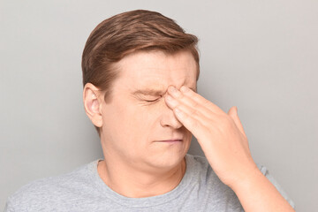 Portrait of tired man touching bridge of his nose with hand