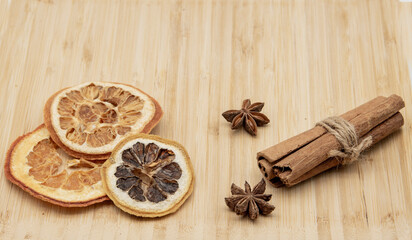 Cinnamon sticks, star anise, and dried oranges lie on a tray.