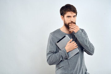 A man in a gray sweater a tablet in the hands of emotions Internet technology lifestyle light background