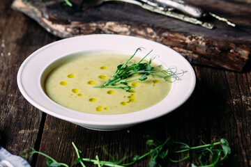Cream soup with fresh green peas in a white plate