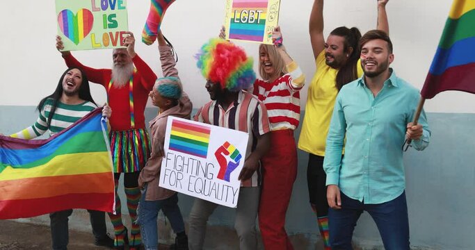 Gay people dance with banners and rainbow flags at pride party outdoor - Lgbt concept