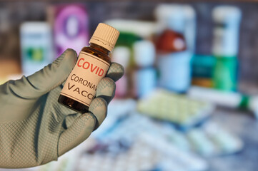 Hand with blue glove holding a flask with vaccine. Coronavirus vaccine in a flask.
