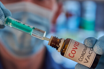 Researcher with face mask fills a syringe with medication. Medical filling up a syringe with vaccine. Syringe with vaccine. Corona treatment. Coronavirus vaccine. Biontech vaccine.