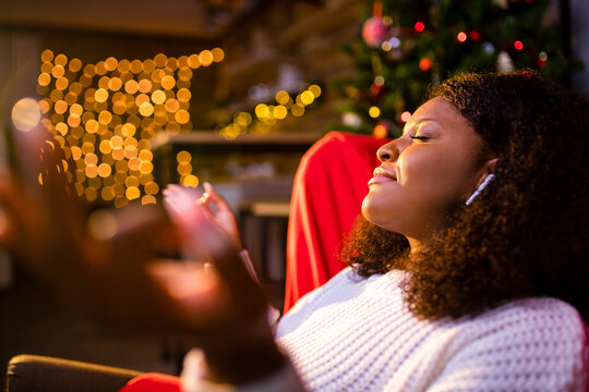 Serene young woman closed eyes relaxing leaned on couch modern wireless headphones in an ear pods