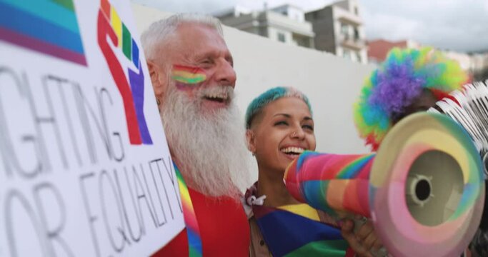 Gay people dance with banners and rainbow flags at pride party outdoor - Lgbt concept