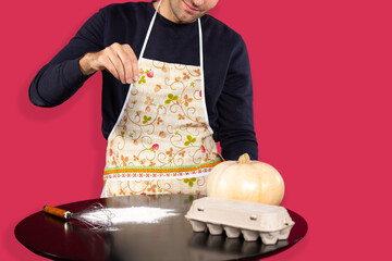 A man in the kitchen sprinkles flour on the table, starting to cook pies with pumpkin. Combat...