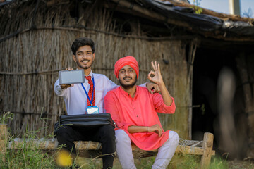 Young indian bank officer showing mobile screen with farmer