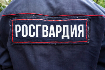 Back of a soldier of Russian Guard wearing military camouflage uniform with label Russian Guard