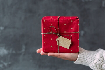 New Year's gift in a red box in the hands of a girl
