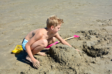 Little boy builds castle in the sand