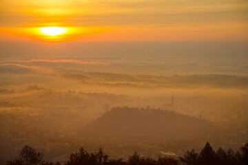 Amazing foggy sunrise over the city of Graz with Schlossberg hill and Church of the Sacred Heart of Jesus tower, in Styria region, Austria. Panoramic view from Plabutsch mountain on autumn morning.