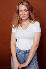 Obraz premium young pretty girl with blond curly hair posing cheerful on brown background, lifestyle people concept