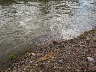 Abstract detail from the river, fast turbulent and wavy water and gravel shore during the day.