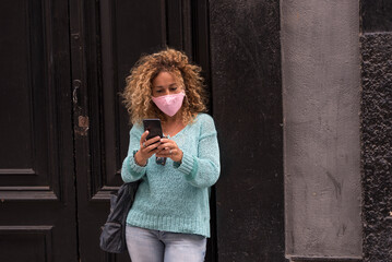 Fototapeta premium Adult woman wear protection mask against covid-19 coronavirus virus emergency - protect yourself people with anti virus accessory - female in the town with phone reading news about health