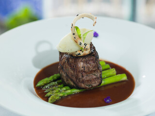 Tasty filet mignon on a bed of asparagus in black pepper sauce.