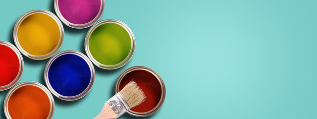 renovation concept. colorful opened paint cans with brush on pastel cyan background. banner copy space