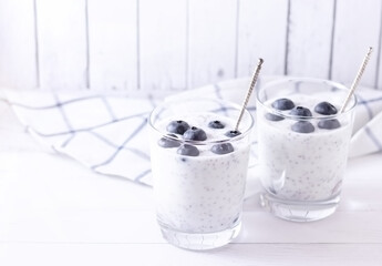 Natural homemade organic yogurt with natural berries and chia seeds in glass glasses on a light background. Place for text.
