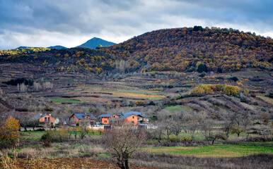 Serene Spanish rural landscape, with distant colorful village and green mountains.