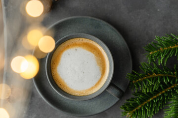 Obraz na płótnie Canvas A photo of cappuccino with chocolate donuts and christmas decoration. Grey cups on the grey table and a grey wall. Place for text