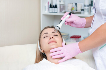 Hardware cosmetology. Close up picture of lovely young woman with closed eyes receiving rf lifting procedure in beauty salon.