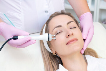 Hardware cosmetology. Close up picture of lovely young woman with closed eyes receiving rf lifting procedure in beauty salon.