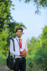 Young indian banker holding clay piggy bank in hand