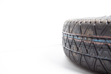 Close-up of the tread of a spare tire of a car on a white background in a photo studio with summer tires. Spare tire for replacement during seasonal car repair in a workshop or garage.