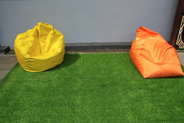 Bean Bag is a chair filled with styrofoam beads and without a frame, lying on a green carpet on the porch of the house