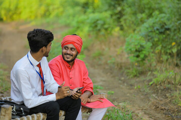 Young indian banker discuss with farmer at field
