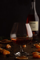 A glass of cognac and the bottle. A Christmas photo with lights and orange