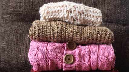Fototapeta na wymiar Stack of colorful winter warm clothes on brown background